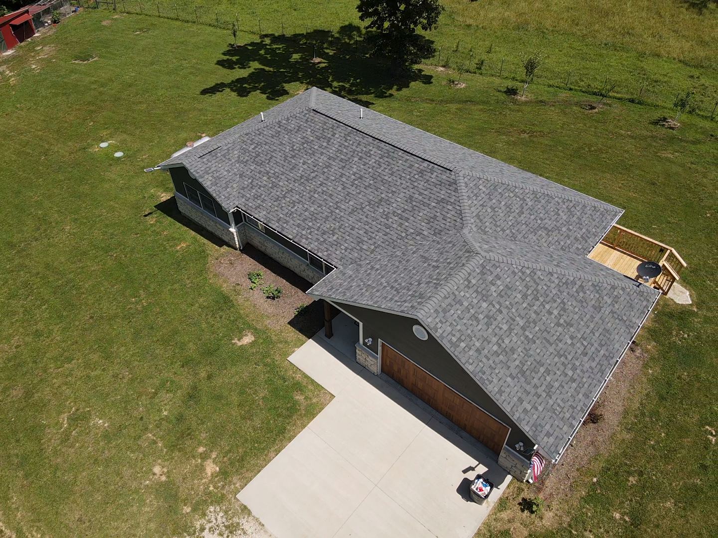 Overhead view of a house with a gray roof and a concrete driveway on a grassy landscape.